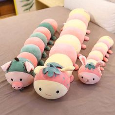 several stuffed animals laying on top of a bed next to each other in the shape of caterpillars