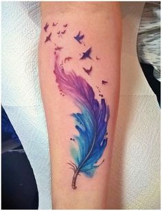 a blue and purple feather with birds flying in the sky on someone's leg