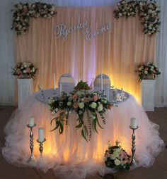 the table is set up with flowers and candles for an elegant wedding reception in front of a backdrop