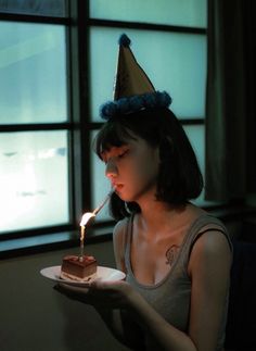 a woman sitting in front of a window holding a plate with a piece of cake on it