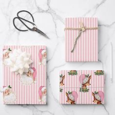 pink and white striped wrapping paper with scissors on the top, next to it is a pair of scissors