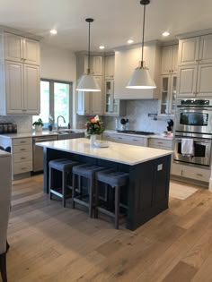 a large kitchen with an island in the middle and three stools at the end