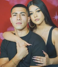 a man and woman are posing for a photo in front of a red background with stars