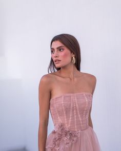 a woman in a pink dress standing next to a white wall