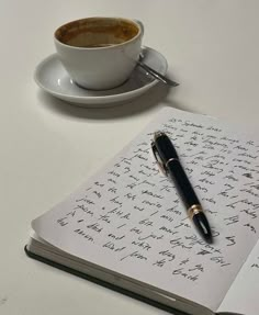 a cup of coffee sitting on top of a table next to an open notebook and pen