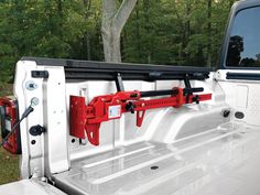 the front end of a white truck with two red hitch bars