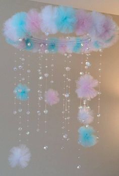 a chandelier with blue and pink feathers hanging from it's sides in a room