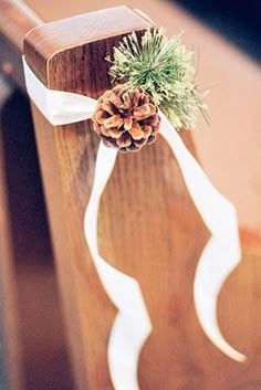 a pine cone tied to the back of a wooden bench with a white ribbon around it