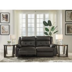 a living room scene with focus on the reclining sofa and love seat, along with two end tables