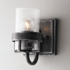 a light that is on the wall next to a glass candle holder with two lights