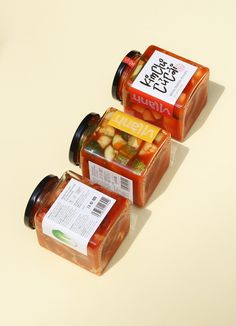 three jars of food sitting on top of a table next to each other with labels