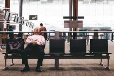 an old man sitting on a bench in the airport waiting for his flight to arrive