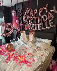 a woman laying on top of a bed surrounded by balloons and streamers in the shape of letters