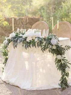 a table with flowers and greenery is set up for an outdoor wedding reception in the woods