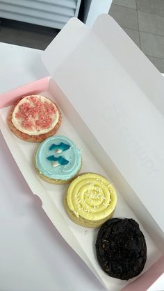 an open box with three different flavored pastries in it on top of a table