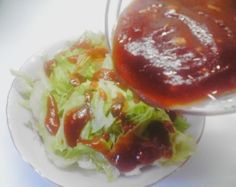 lettuce and tomato sauce on a white plate with a bowl of ketchup