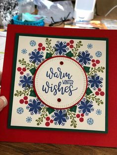 a hand holding up a card with the words warm wishes on it and snowflakes