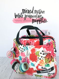 a colorful floral bag sitting on top of a wooden table next to a sign that says, mixed media bible journaling supplies