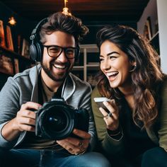 a man and woman sitting next to each other with headphones on while looking at a camera