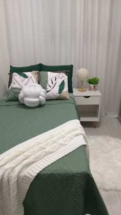 a bed with green sheets and pillows on top of it next to a night stand