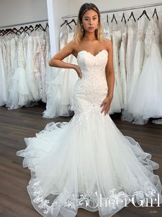 a woman in a white wedding dress standing next to dresses on display at a bridal shop