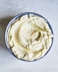 a blue bowl filled with whipped cream on top of a white countertop next to a knife