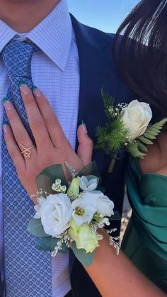 a man and woman wearing wedding rings holding hands with flowers on their fingers, both dressed in green