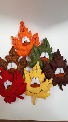 a group of stuffed animals sitting next to each other on a white surface with leaves painted on them