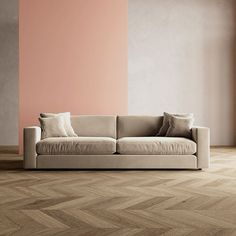 a white couch sitting on top of a wooden floor next to a pink painted wall