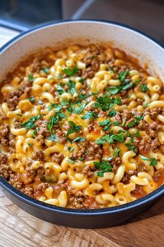 a bowl filled with pasta and meat on top of a wooden table