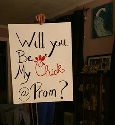 a person holding up a sign that says will you be my chick at prom?