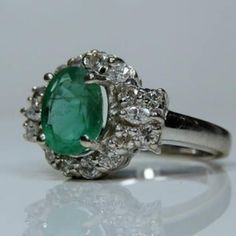 an emerald and diamond ring on a white surface