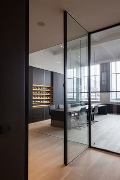 an empty conference room with glass walls and wooden flooring is seen from the doorway