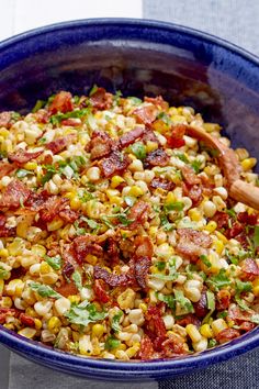 a blue bowl filled with corn and bacon