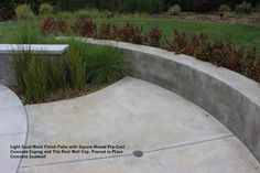 a concrete bench sitting next to a lush green field