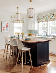 a kitchen island with four stools in front of it and flowers on the counter