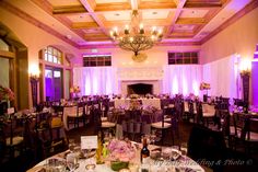 a banquet hall with tables and chairs set up for an event or function, purple lighting is on the ceiling