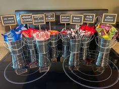 several buckets filled with candy sitting on top of a counter next to small signs