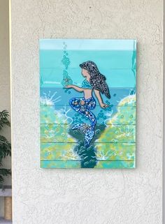 a painting on the side of a building with a mermaid holding a fish in it's hand