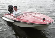 a man driving a red and white boat in the water