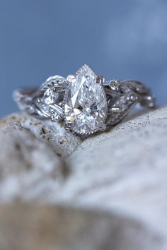 a close up view of a diamond ring on top of a rock with blue sky in the background