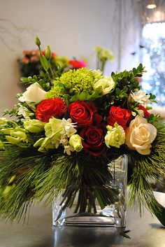 a vase filled with red and white flowers on top of a table next to a window