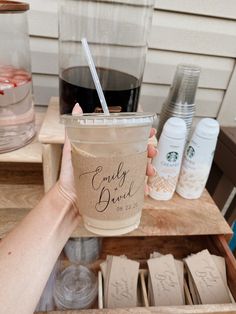 a person holding up a cup with a straw in it and some other items nearby