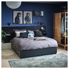 a bedroom with blue walls and pictures on the wall above the bed, along with an area rug