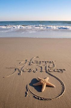 a happy new year written in the sand with a starfish