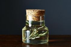 a glass bottle filled with water and some green leaves on top of a wooden table