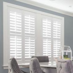 a dining room table and chairs with white shutters