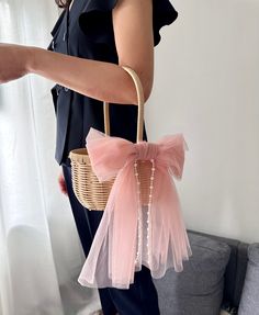 a woman holding a basket with a pink bow on it