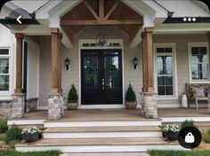 front porch with steps leading up to the entry door and two planters on either side