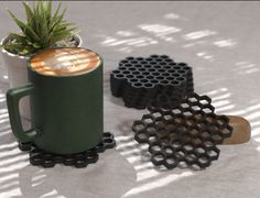 a coffee mug sitting on top of a table next to two black coasters and a potted plant